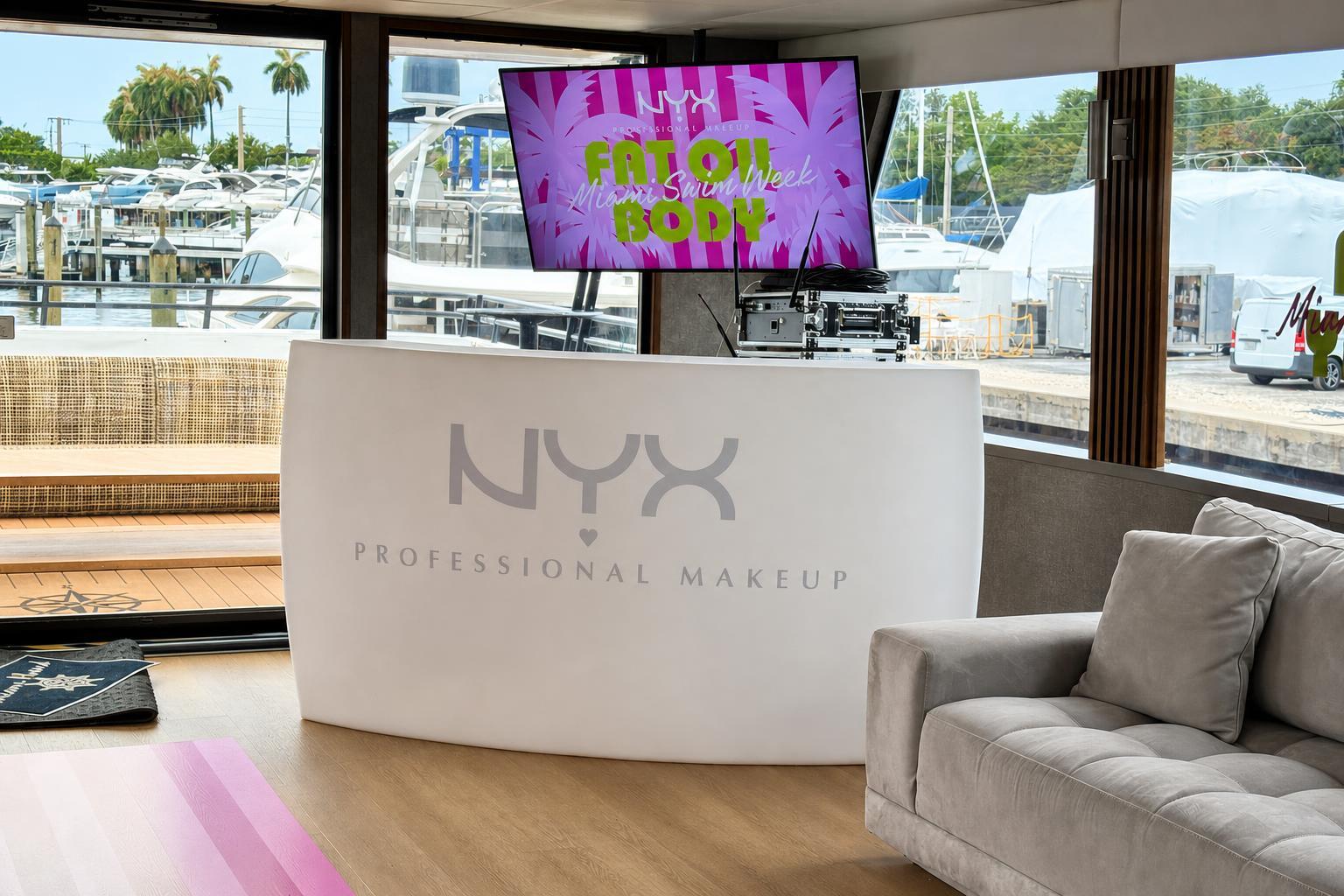 White curved bar wrapped with NYX Professional Makeup branding and a Fat Oil Body display screen on a Miami yacht